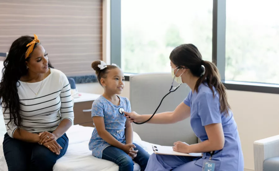 Doctor examining child patient with mother present in medical clinic
